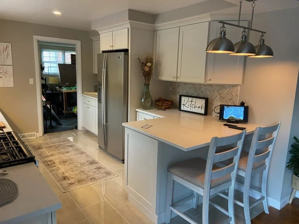 Remodeled kitchen with a quartz peninsula, shaker cabinets and pendant lighting, completed by JJK Construction