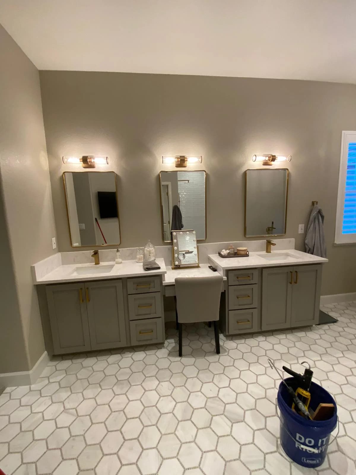 Remodeled bathroom with a double vanity, brass fixtures and hexagon tile flooring, completed by JJK Construction