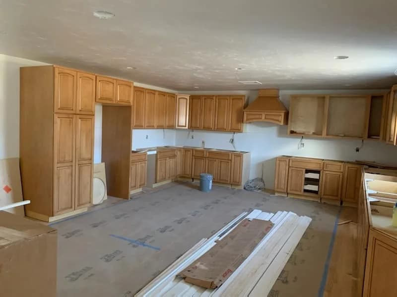 Kitchen cabinetry installation in progress with protected flooring on a JJK Construction job site